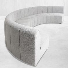 a curved couch sitting on top of a white floor next to a wall in a room