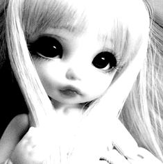 a black and white photo of a doll with long blonde hair