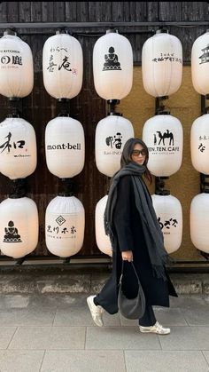 a woman is walking in front of many white lanterns