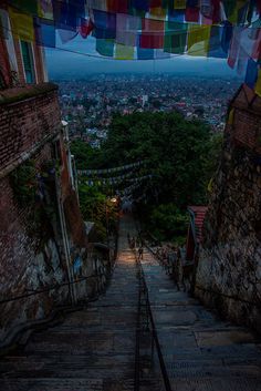 stairs leading up to the top of a building with colorful flags hanging from it's sides