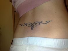 a woman's lower back tattoo with an ornamental design on her left side ribcage