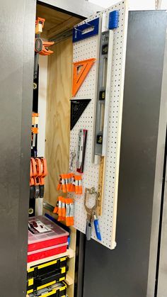 a tool cabinet with tools hanging on the wall and pegs attached to the door