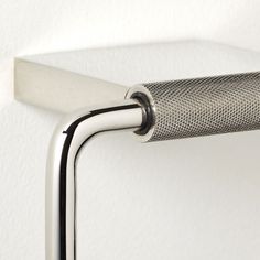 a close up of a metal handle on a white wall with a black and silver object in the background