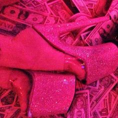 pink glitter shoes are laying on top of money