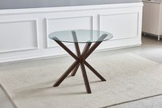 a glass table sitting on top of a rug in front of a white wall and floor