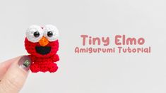 a hand holding a tiny crocheted elmo