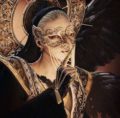 a woman wearing a mask and holding a piece of jewelry in her hand with wings on it