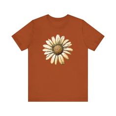 A comfortable and lightweight T-Shirt featuring an illustration of a daisy.  This casual and versatile tee is perfect for everyday wear and layering, giving off a laid-back and nature-inspired vibe. Ideal for nature lovers, garden enthusiasts, and those who appreciate floral designs. Perfect for Earth Day, Mother's Day, or as a spring/summer wardrobe staple. Product features - Made with 100% Airlume combed and ring-spun cotton for breathability - Retail fit for casual and semi-formal settings - Ribbed knit collar with seam for shape retention - Shoulder tape for stability and prevent stretching - Tear-away label for minimized skin irritations Care instructions - Machine wash: cold (max 30C or 90F) - Non-chlorine: bleach as needed - Tumble dry: low heat - Iron, steam or dry: medium heat - D Spring Daisy Print Graphic Tee, Casual Sunflower Design T-shirt With Relaxed Fit, Casual Sunflower Design T-shirt In Relaxed Fit, Casual Sunflower Design Crew Neck T-shirt, Casual Sunflower Design Relaxed Fit T-shirt, Casual Relaxed Fit Sunflower T-shirt, Casual Relaxed Fit T-shirt With Sunflower Design, Spring Cotton T-shirt With Sunflower Design, Spring Sunflower Design T-shirt In Relaxed Fit