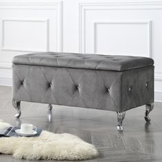 a gray bench sitting on top of a hard wood floor next to a white rug