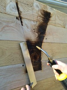 someone using a pair of scissors to cut up wood planks on a house wall