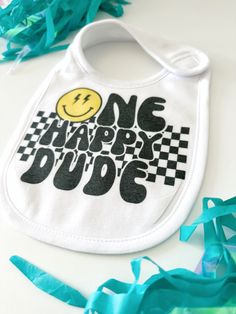 a bib that says one happy dude with a smiley face on it and blue streamers