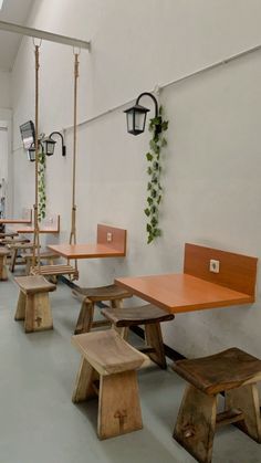 an empty restaurant with wooden tables and benches in front of the wall, hanging planters on either side