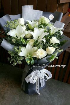 a bouquet of white flowers sitting on top of a blue box with ribbon around it