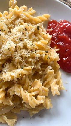 pasta with sauce and parmesan cheese on a plate next to ketchup