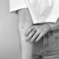 a woman's hand with a small tattoo on her left arm and the number thirteen