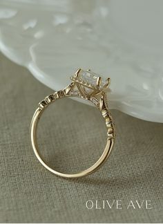 a gold engagement ring with an oval cut diamond in the center and beaded details around the band