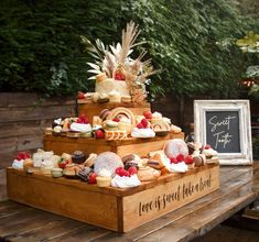 a wooden table topped with three tiered trays filled with cakes and pastries