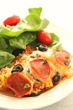 a white plate topped with slices of pizza next to spinach leaves and cherry tomatoes