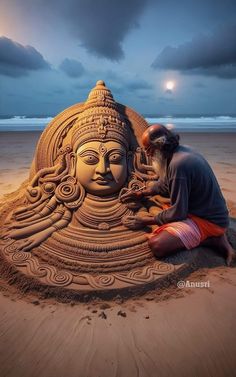 a man sitting on top of a sandy beach next to a sand sculpture