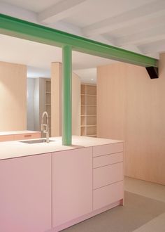 an empty kitchen with pink cabinets and green beams