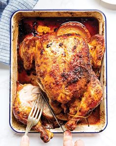 a person holding a fork in a roasting pan filled with chicken