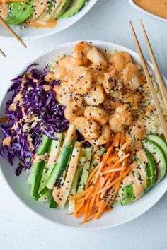 two plates filled with shrimp and veggies next to chopsticks on the side