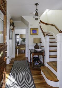 an entry way with stairs and a rug on the floor in front of a table