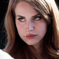 a close up of a woman with long hair and blue eyes looking at the camera