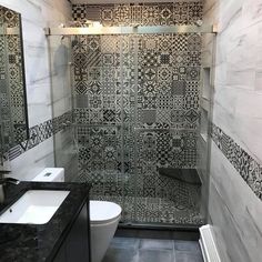 a bathroom with black and white tiles on the walls, shower stall and sink area