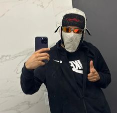 a man wearing a face mask while taking a selfie in front of a marble wall