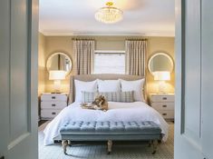 an open door leading to a bedroom with a white bed and blue upholstered bench