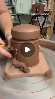 a person is making a vase out of clay