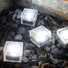 four ice cubes sitting on top of some rocks