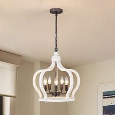 a white chandelier hanging from a ceiling in a living room with beige walls