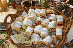 a basket filled with sandwiches on top of a table next to plates and utensils