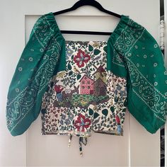 a green blouse hanging on a white door with an ornate design and tassels