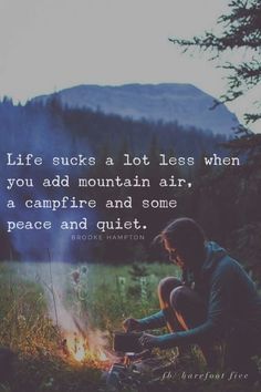 a person sitting next to a campfire with a quote about life such as a lot less when you add mountain air, a campfire and some peace and quiet