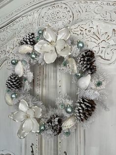 a wreath with pine cones and white flowers