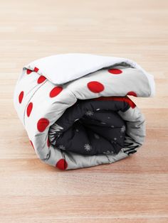 an unmade blanket with red polka dots on it sitting on top of a wooden floor