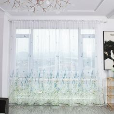 a living room filled with furniture and a window covered in sheer curtaining next to a painting on the wall