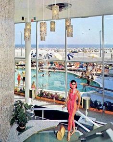 a woman standing in front of a swimming pool with lots of people on the water