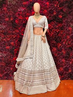 Be your own fashionista with this ivory lehenga. The lehenga is encrusted with very desirable jardozi embroidery and sequins work which is eye catching! Key Features: Color: Ivory Lehenga Fabric: Luxurious silk or similar Embellishments: Intricate silver or gold embroidery or embellishments Silhouette: Flowing and graceful Dupatta: Sheer dupatta with intricate border Designer White Dola Silk Lehenga, White Dola Silk Lehenga For Designer Wear, Designer Zari Work Choli In Off White, Designer Off White Choli With Intricate Embroidery, Elegant Dola Silk Choli With Sequins, Designer Zari Work Off-white Choli, Designer White Choli With Intricate Embroidery, Designer Off-white Choli With Zari Work, Designer Wear Off-white Choli With Zari Work