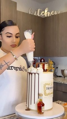 a woman is decorating a cake with white frosting and chocolate decorations on it