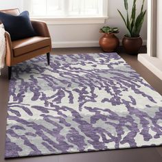 a purple and white rug in a living room next to a chair with a potted plant