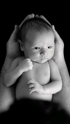 a man holding a baby up to his face in front of the camera, with one hand on it's head