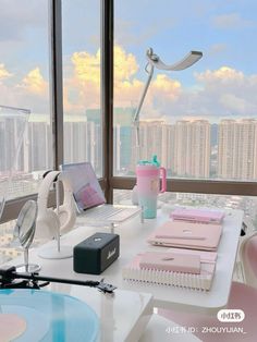 a desk with various items on it in front of a large window overlooking the city