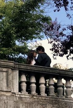 a man and woman standing on top of a bridge