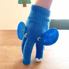 an elephant made out of blue knitted socks on a wooden table with a tree in the background