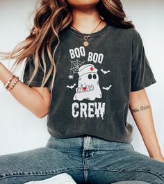 a woman sitting on the floor with her legs crossed and wearing a t - shirt that says boo boo crew