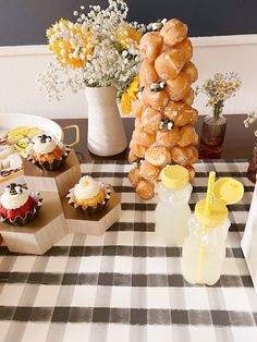 a table topped with donuts and cupcakes next to vase filled with baby's breath